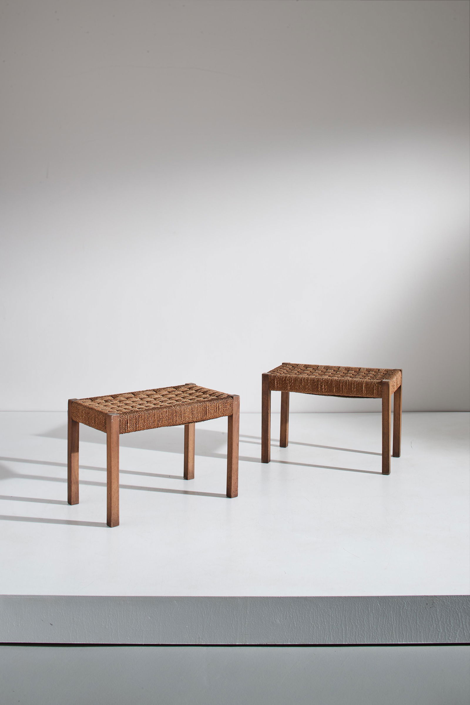 EMANUELE RAMBALDI (ATTRIB. A): Coppia di sgabelli razionalisti. Legno di noce, corda di canapa intrecciata. cm 40x60x35 A PAIR OF OTTOMANS ATTRIBUTED TO E. RAMBALDI Buone condizioni generali. Graffi, normali segni di usura dovuti a