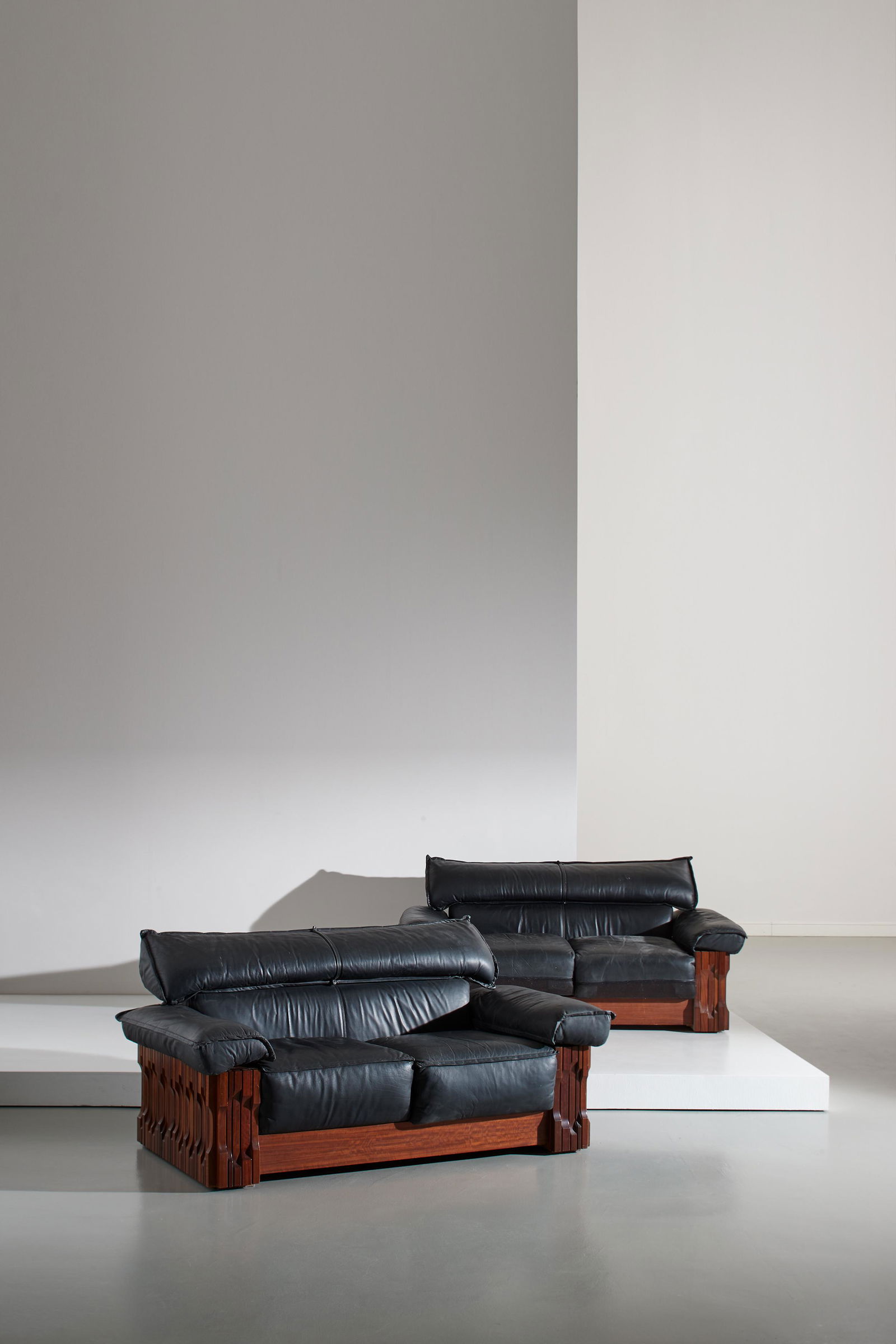 LUCIANO FRIGERIO: Due divani della serie Norman. Legno esotico, pelle imbottita. Produzione Frigerio di Desio anni '70. cm 86x176x100 A PAIR OF SETTEES BY L. FRIGERIO Buone condizioni generali. Piccoli graffi, normali