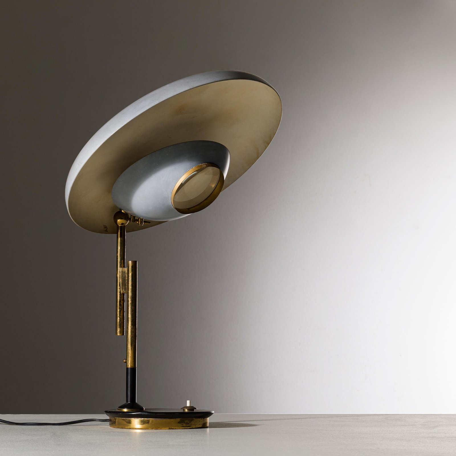 OSCAR TORLASCO: Lampada da tavolo mod. 555. Ghisa, metallo smaltato, ottone, vetro lenticolare. Produzione Lumi Milano, anni '50. Etichetta della manifattura. cm 52x36x36 A TABLE LAMP BY O. TORLASCO Catalogo di produ