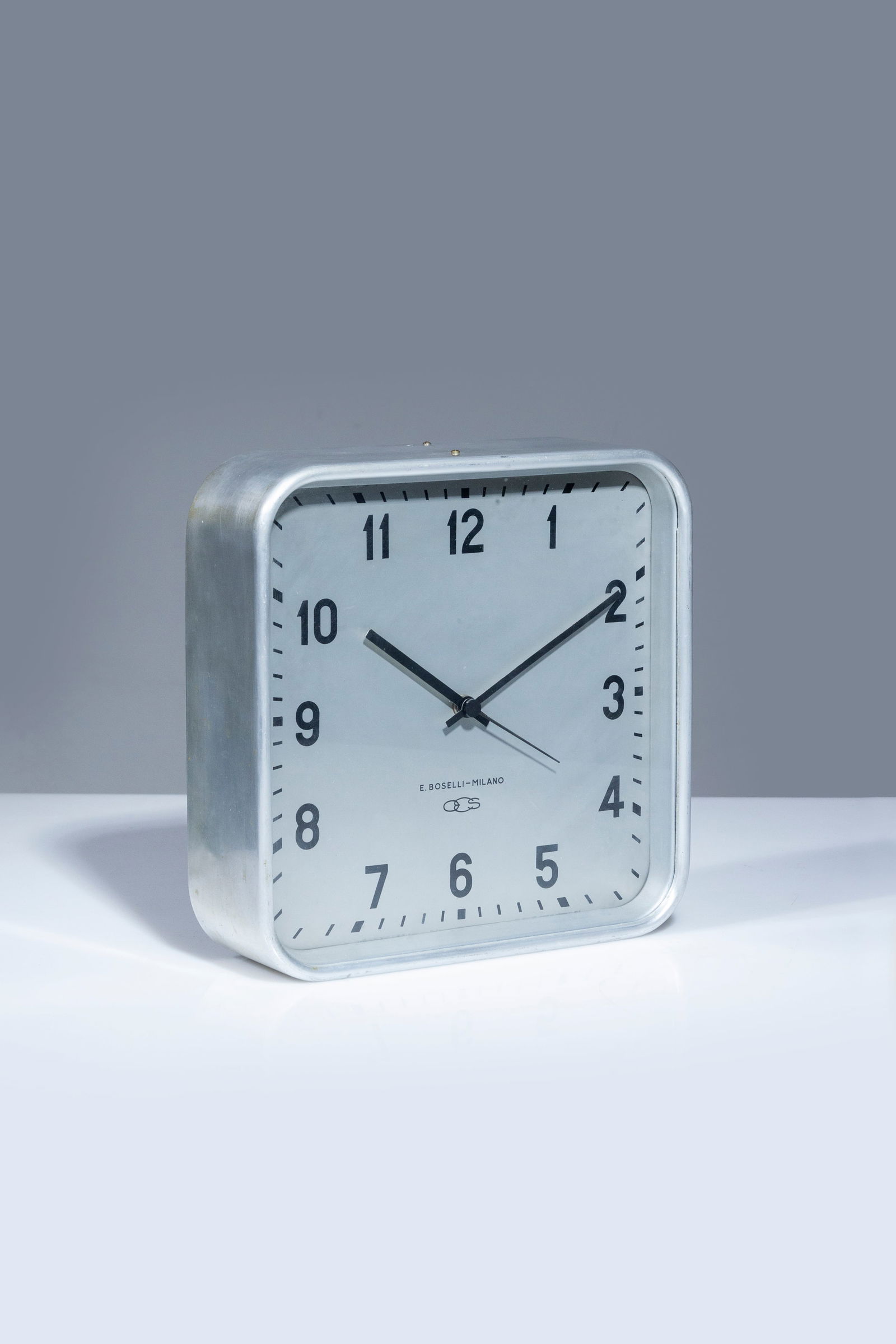 GIO PONTI: Orologio da parete. Alluminio, metallo smaltato. Produzione Boselli, anni '50. Firma della manifattura sul quadrante. cm 28x28x9 A WALL CLOCK BY G. PONTI Cfr.: U. La Pietra, Gio Ponti. L'arte si innam