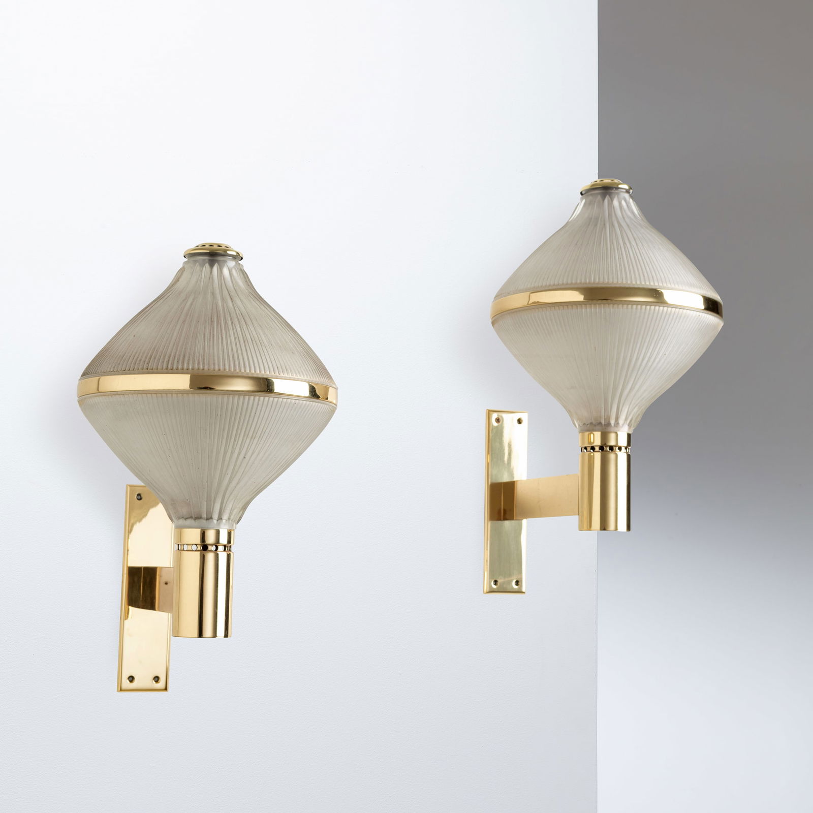 B.B.P.R: Coppia di lampade da parete Polimnia. Ottone, vetro pressato. Produzione Artemide anni '60. cm 50x26x40 A PAIR OF WALL LAMPS BY B.B.P.R Buone condizioni generali. Piccole righe, leggeri graffi, normal