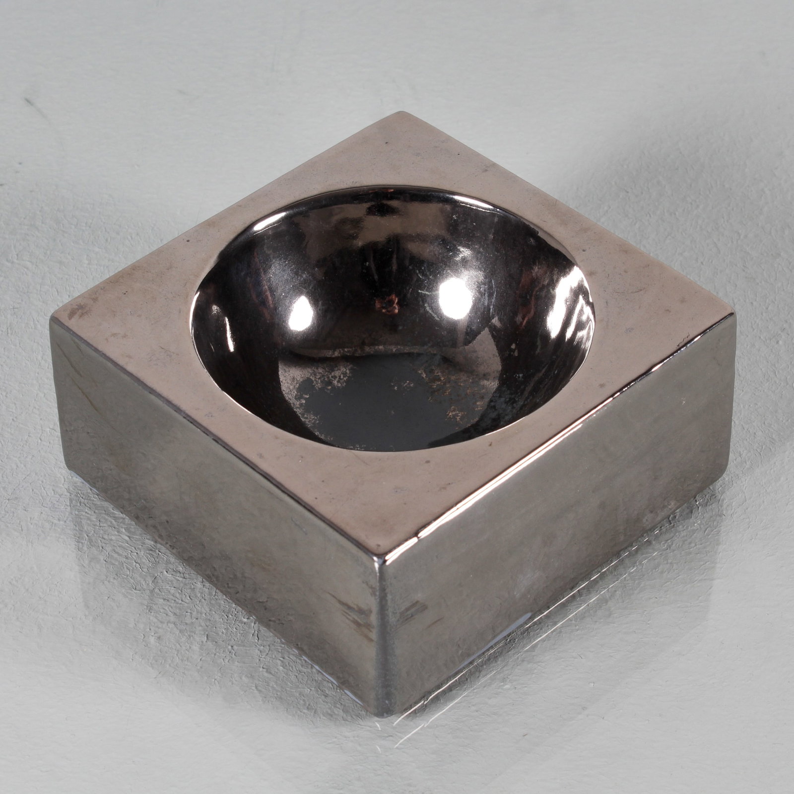 ETTORE SOTTSASS (NEL GUSTO DI): Posacenere. Ceramica smaltata. Italia, anni '60. Sotto la base impresso 'Italia'. cm 5x11,5x11,5 AN ASHTRAY IN THE MANNER OF E. SOTTSASS Buone condizioni generali, piccole righe, leggeri graffi, norma