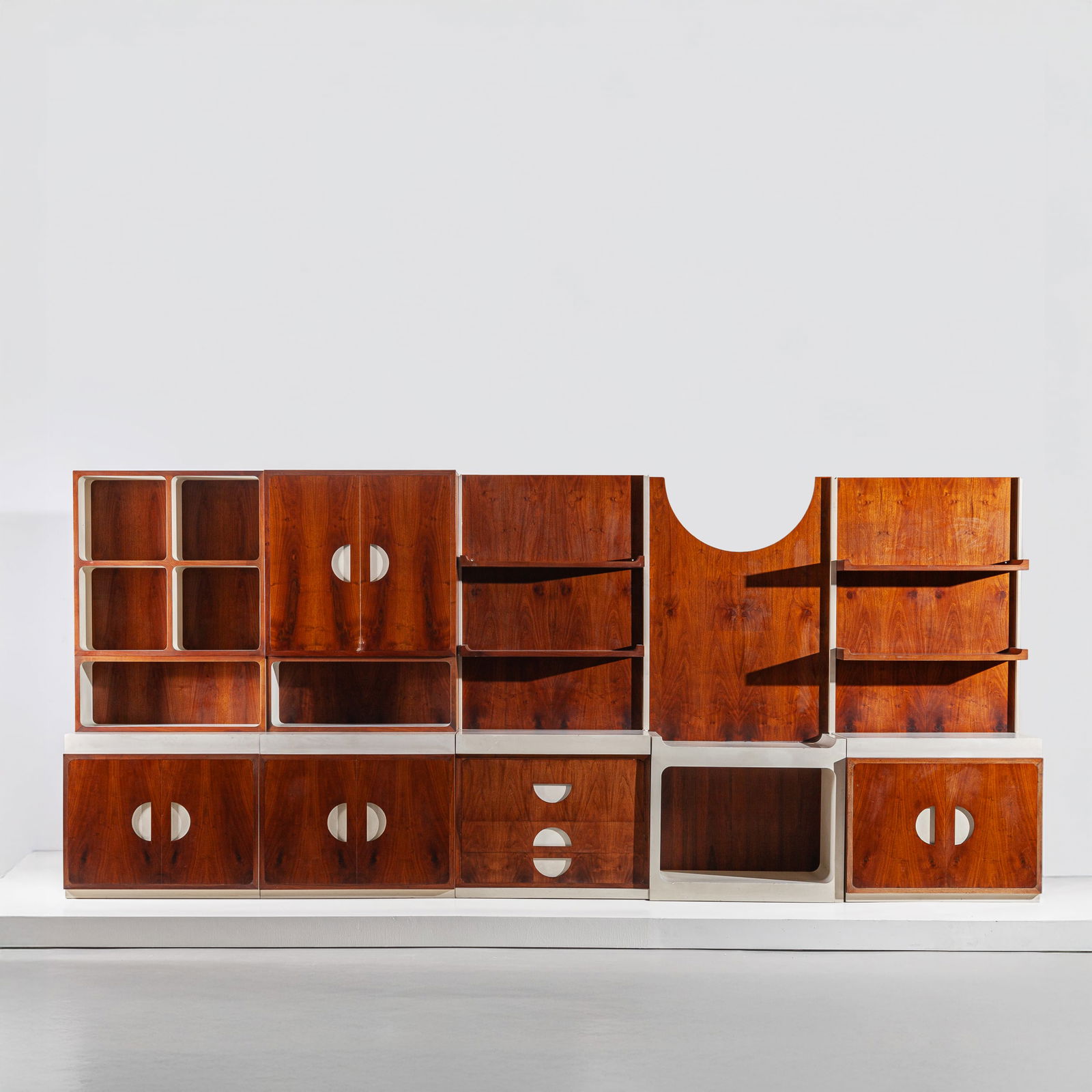 FRANCO CAMPO & CARLO GRAFFI: Parete attrezzata. pezzo unico per una residenza privata. Multistrato laccato e lastronato in legno di noce. Esecuzione Home Torino, anni '60. Decalcomania della manifattura. cm 222x503x50 A BOOKCASE