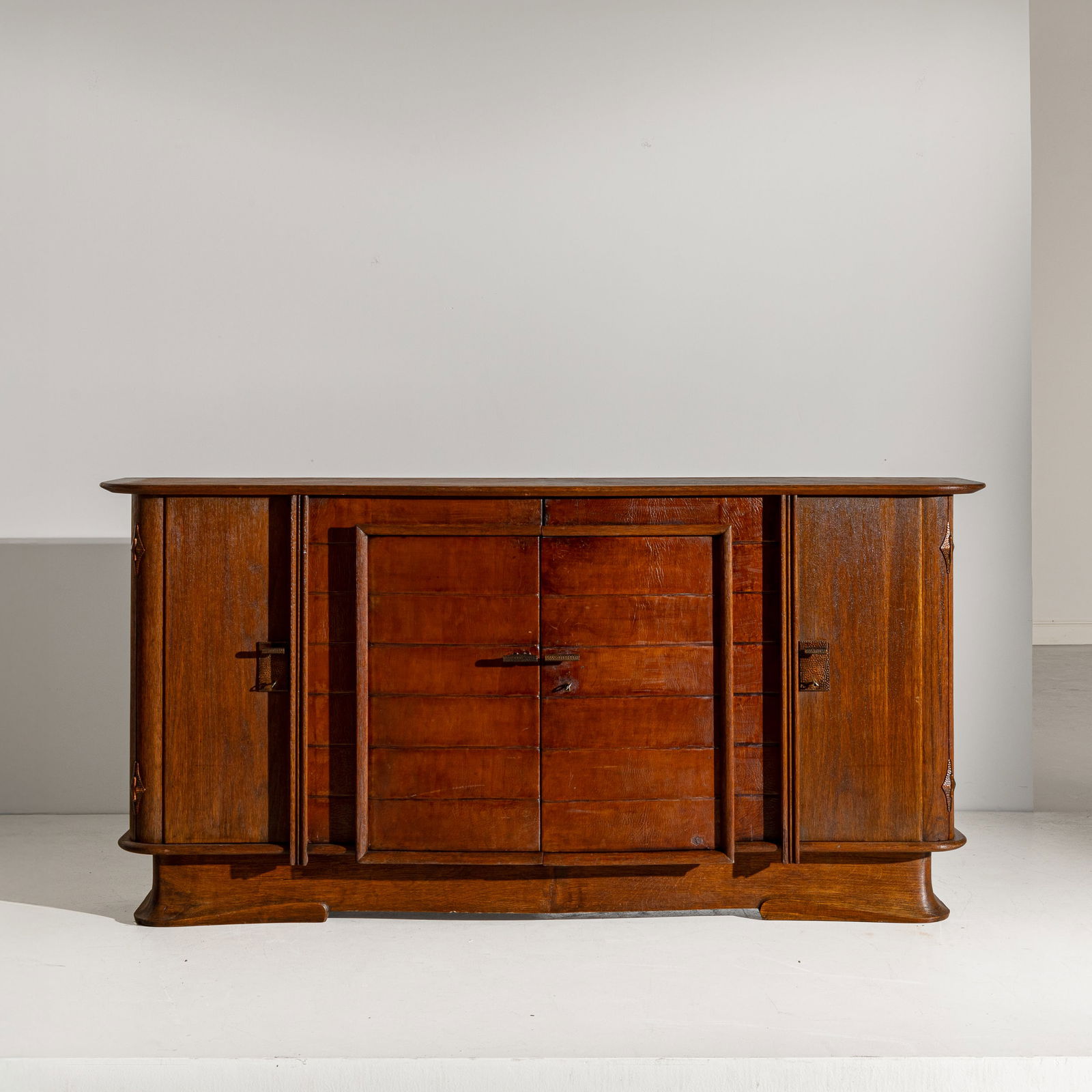 VITTORIO VALABREGA: Grande credenza. Legno di noce, rame sbalzato, legno di rovere massello in parte graffiato, legno di mogano. Esecuzione Atelier dell'Artista anni '30. cm 105x46x212 A SIDEBOARD BY V. VALABREGA Buone,
