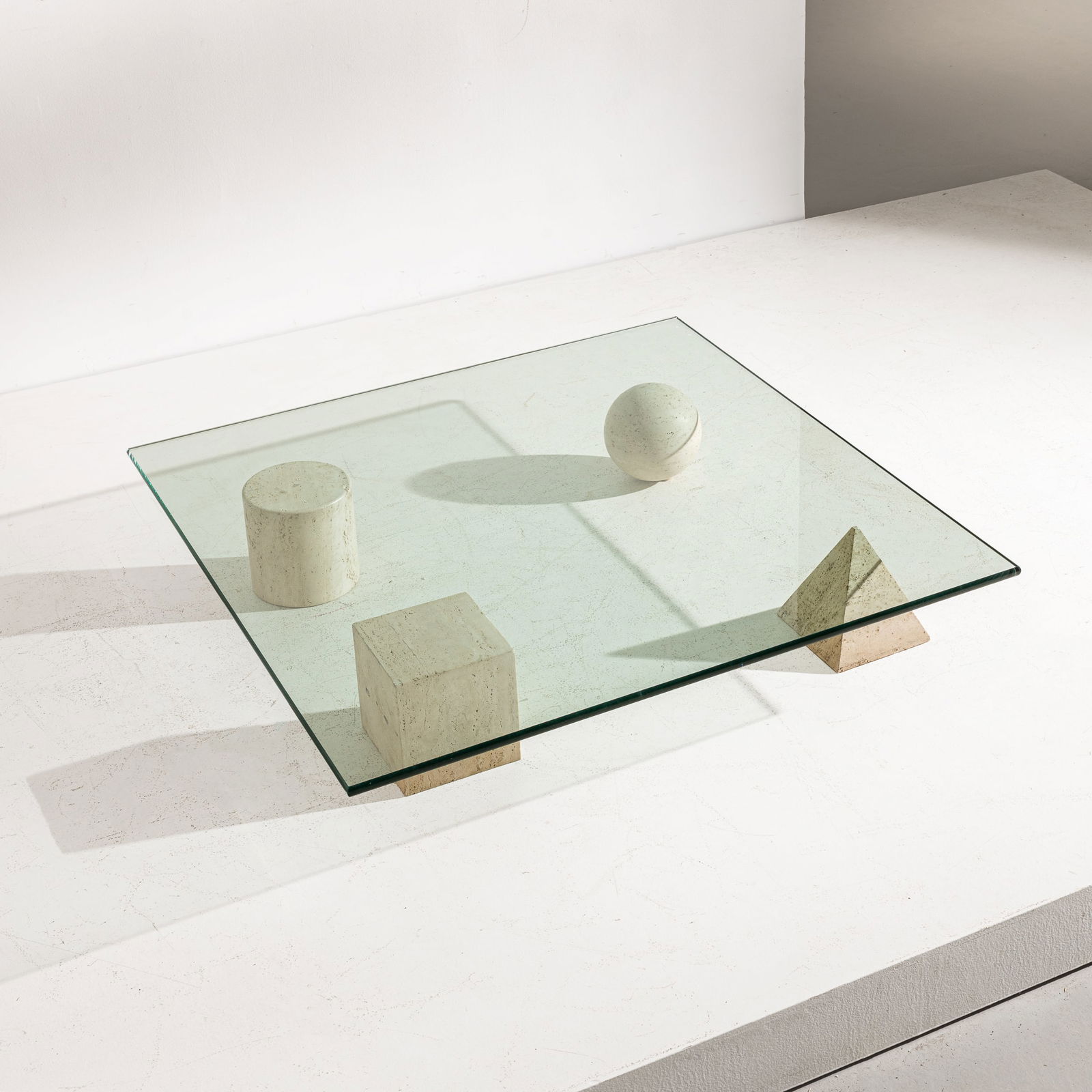 MASSIMO & LELLA VIGNELLI: Tavolino modello Metafora. Travertino, cristallo molato. Produzione Casigliani 1985 circa cm 22x120x120 A LOW TABLE BY L. & M. VIGNELLI G. Gramigna, Repertorio del design italiano per l'arredamento do