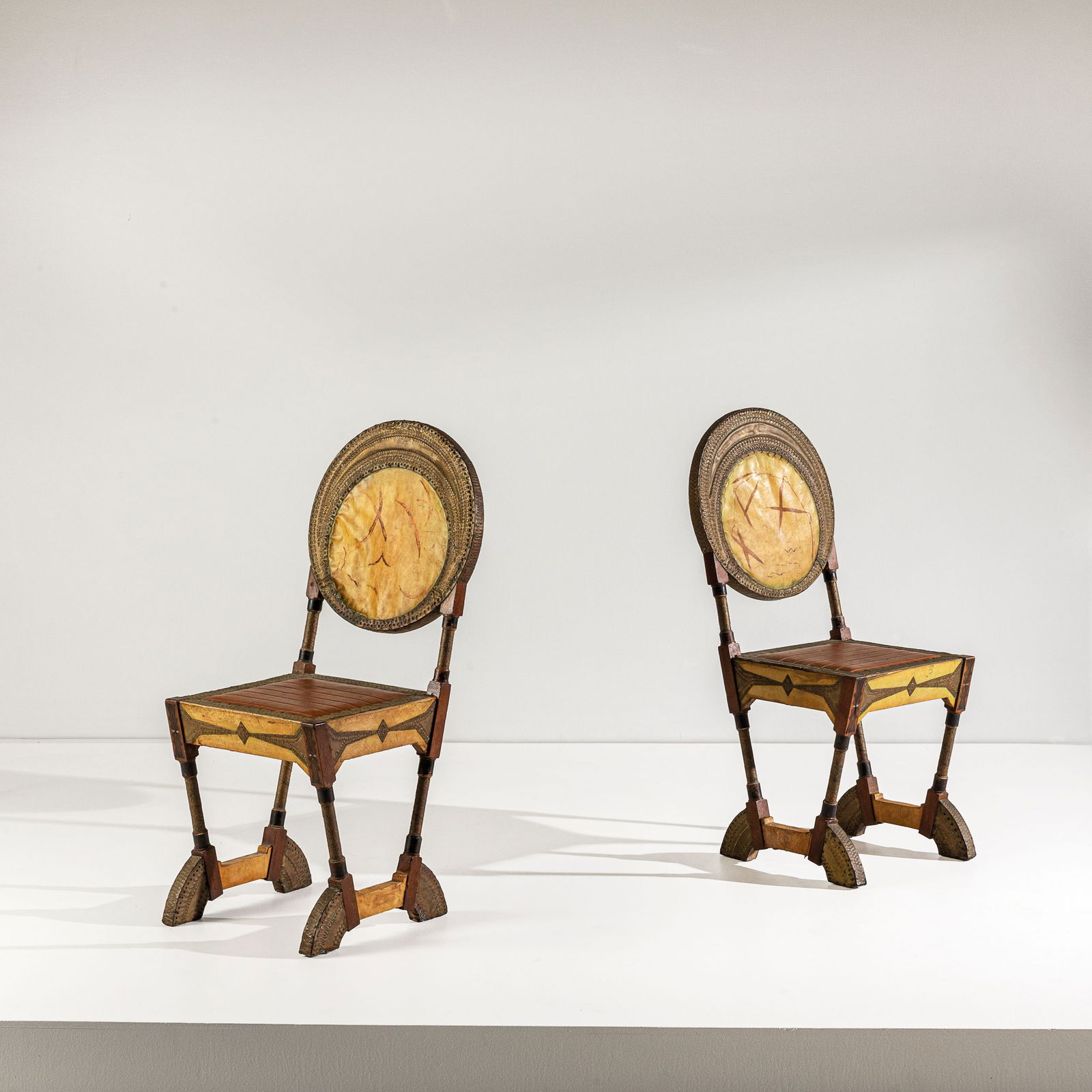 CARLO BUGATTI.: Coppia di sedie. Legno di noce, legno ebanizzato, legno di frutto, osso, peltro, ottone, pergamena dipinta, rame sbalzato. Produzione atelier dell'artista, Parigi, 1900 ca. A PAIR OF CHAIRS BY C. BUGA