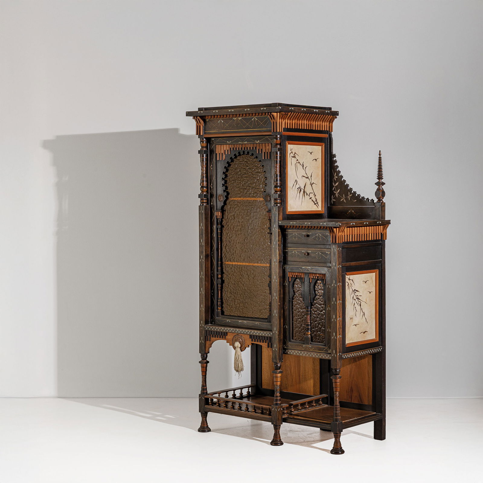 CARLO BUGATTI: Mobile. Legno di noce, legno ebanizzato, legno di frutto, osso, ottone, pergamena dipinta, rame sbalzato, vetro colorato. Atelier dell'Artista, Parigi, 1900 ca. cm 176x8,5x50,5 A CABINET BY C. BUGATTI