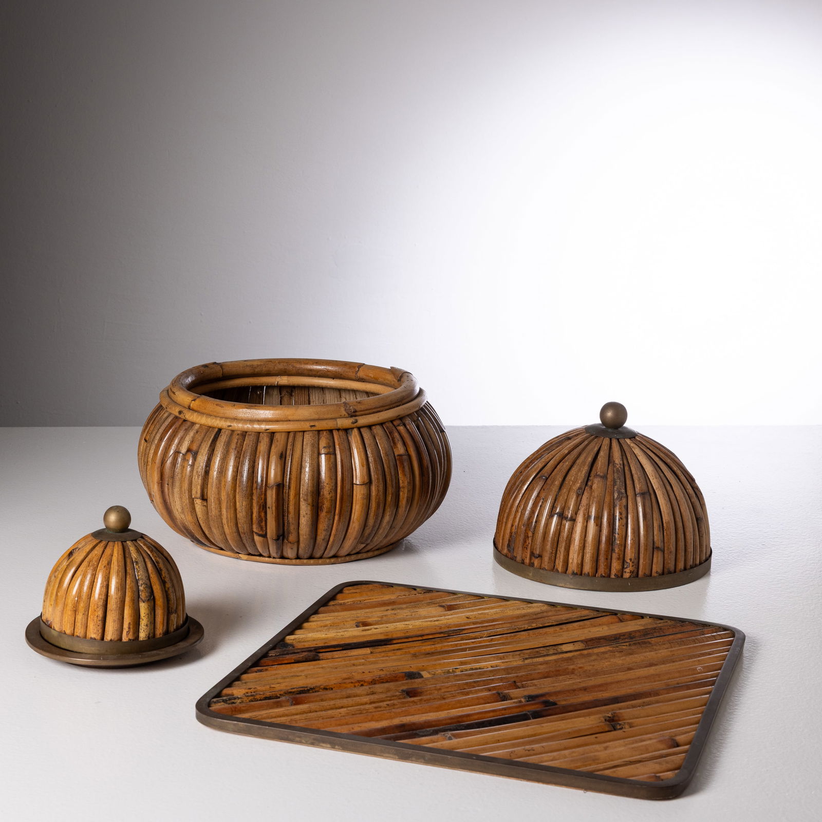 GABRIELLA CRESPI: Set composto due scatole e un vassoio. Ottone, malacca, plexiglass. Italia, anni '70. Firma incisa. Vassoio cm 1x41x41; Calotta cm 12x16; Calotta grande 16x29 ca.; ciotola 18x33 ca. A TABLETOP