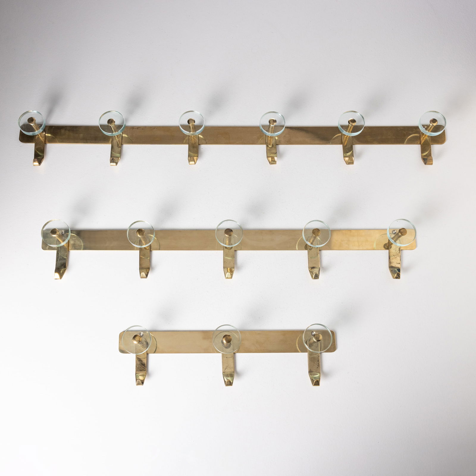 MANIFATTURA ITALIANA: Tre appendiabiti. Ottone, metallo, cristallo colorato molato. Anni '60. cm 12x49x7, 12x88x7, 12x100x7 ca. THREE ITALIAN COAT HANGERS Condizioni molto buone. Righe, segni di usura. Lieve ossidazione. T