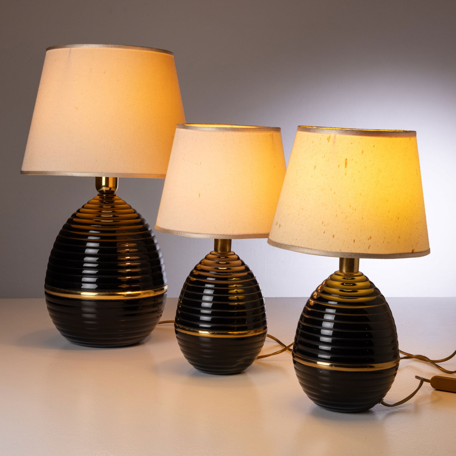 MANIFATTURA ITALIANA: Tre lampade da tavolo. Metallo verniciato, ottone, tessuto. Italia, anni '70. con diffusore 59x33x33; cm 45x25x25 THREE ITALIAN TABLE LAMPS Buone condizioni. Righe, segni di usura, lievi aloni, lieve