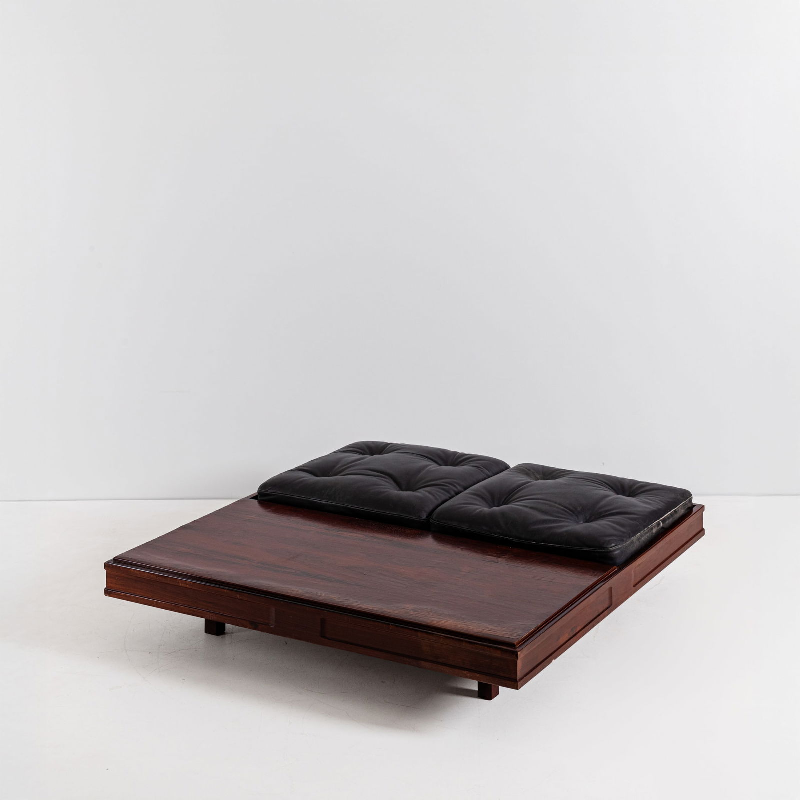 MANIFATTURA ITALIANA: Grande tavolino. Legno esotico, metallo, vinilpelle imbottita. Italia anni '60. cm 35x140x140 AN ITALIAN LOW TABLE Buone condizioni generali. Piccole righe, leggeri graffi, normali segni di usura. Tes