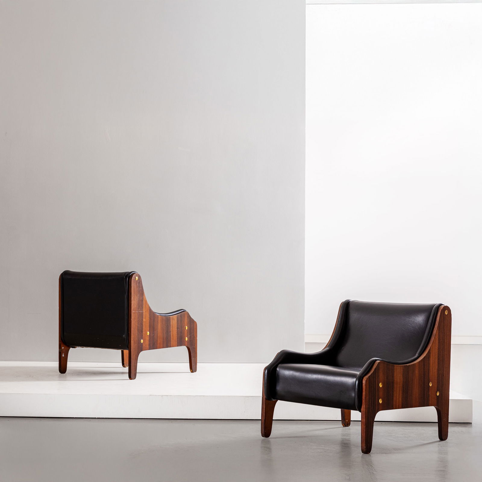 MARCO ZANUSO: Coppia di poltrone mod. Milord. Legno impiallacciato in legno esotico, ottone, vinilpelle imbottita. Produzione Arflex, Italia, 1950 ca. cm 80x72x86 A PAIR OFARMCHAIRS BY M. ZANUSO G. Gramigna, Repert