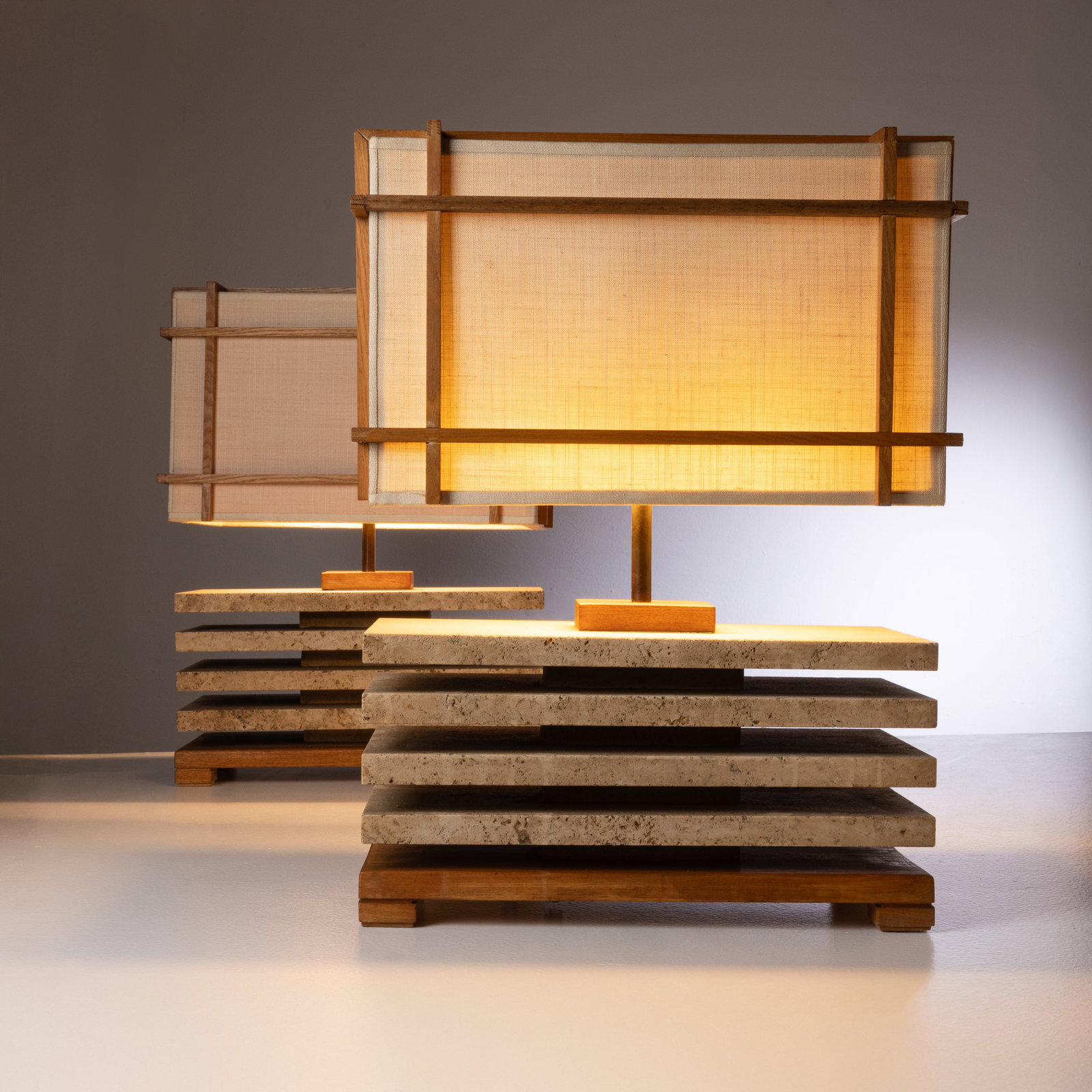 MANIFATTURA ITALIANA: Due lampade da tavolo. Legno di teak, travertino a poro aperto, tessuto. Italia anni '70. cm 55x40x20 TWO ITALIAN TABLE LAMPS Condizioni molto buone. Righe, graffi, piccole mancanze. Aloni e punti