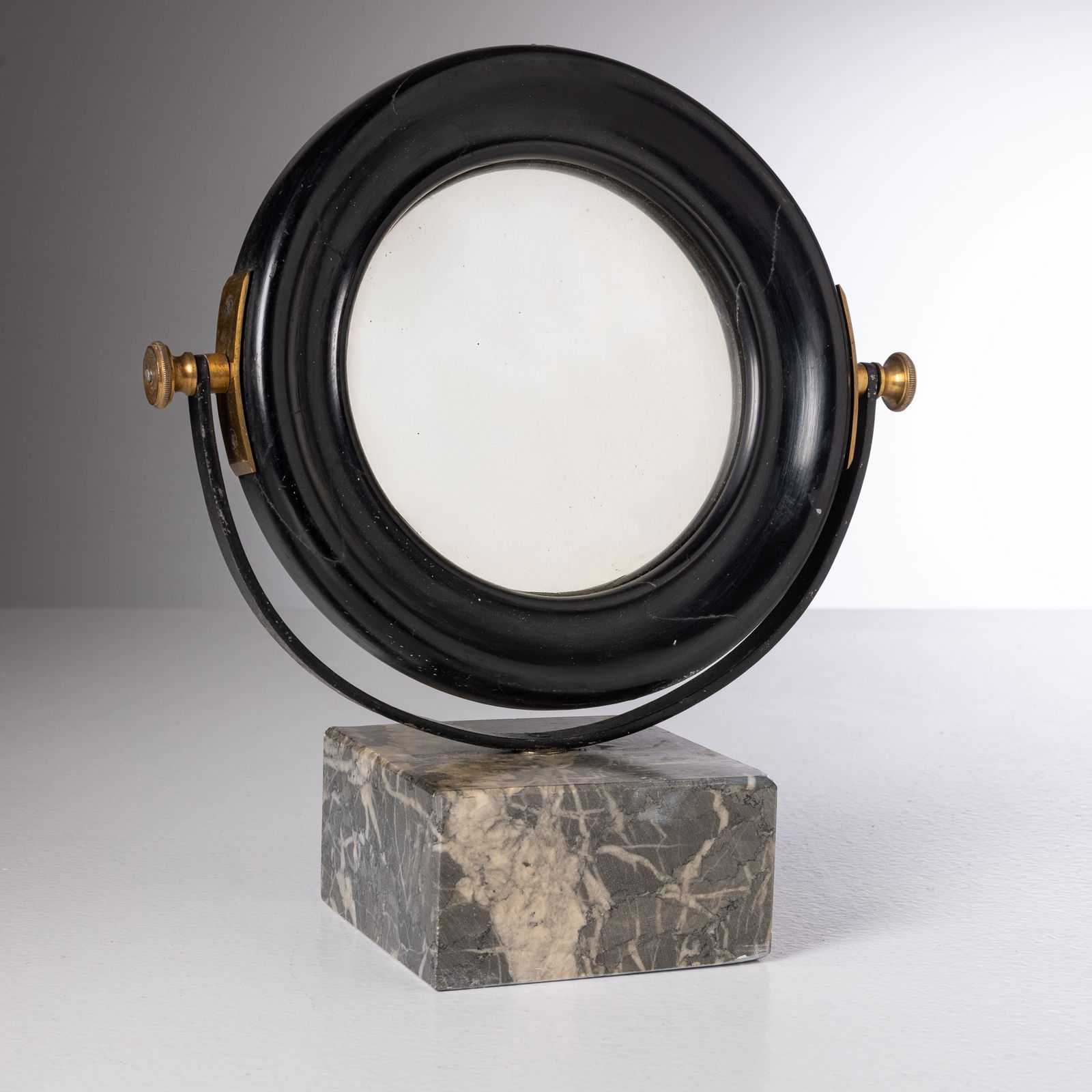 MANIFATTURA ITALIANA: Vanity. Marmo, metallo, ottone, alluminio anodizzato, vetro specchiato e curvato, legno massello ebanizzato. Italia anni '50. cm 33x30x13 AN ITALIAN VANITY MIRROR Buone condizioni. Righe, graffi, segn
