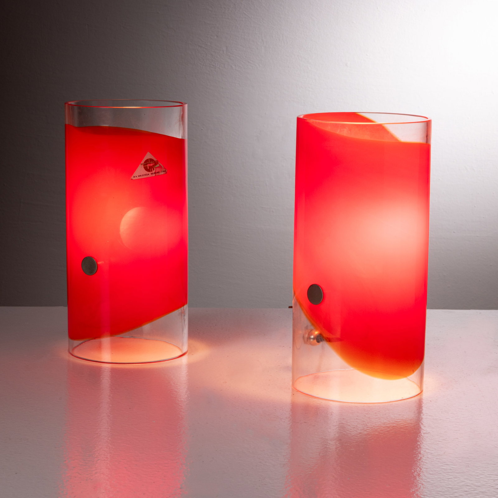 CARLO NASON: Coppia di lampade da tavolo. Metallo nichelato, vetro trasparente con inclusione di fascia colorata. Produzione A.V. Mazzega anni '60 Etichetta del produttore. cm 25x12 A PAIR OF TABLE LMAPS BY C.