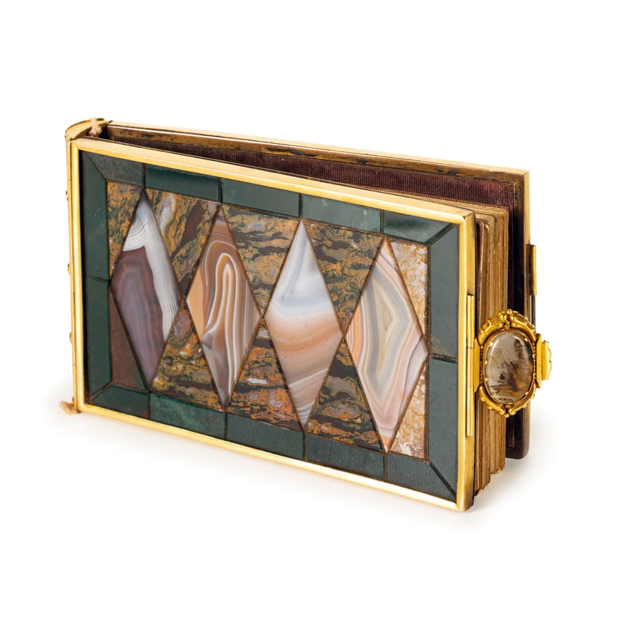 TACCUINO IN MARMI E PIETRE DURE MONTATE IN BRONZO: DORATO, XIX-XX SECOLO apribile con chiusura ovale, interamente rivestito da piccole tessere geometriche in pietre dure, diaspri e agate, le bordure a simulare un piccolo libro con all'interno