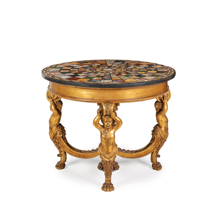 TAVOLO DA CENTRO IN LEGNO SCOLPITO E DORATO, XIX SECOLO: piano circolare in marmi diversi con decoro geometrico a tessere policrome e micromosaico al centro raffigurante rovine del foro romano, supporto con montanti antropomorfi scolpiti a tuttotondo; difet