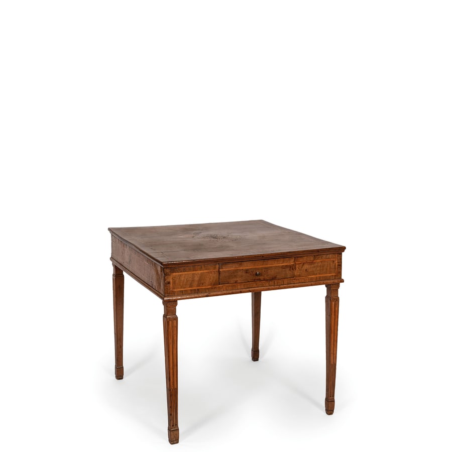 TAVOLO DA CENTRO IN LEGNO DI NOCE, XVIII-XIX SECOLO: piano squadrato centrato da rosone stilizzato e libro a trompe-l'oeil, fasce percorse da riserva filettata e cassetto nel fronte, gambe rastremate e scanalate; usure, difetti, minore fenditura nel pia