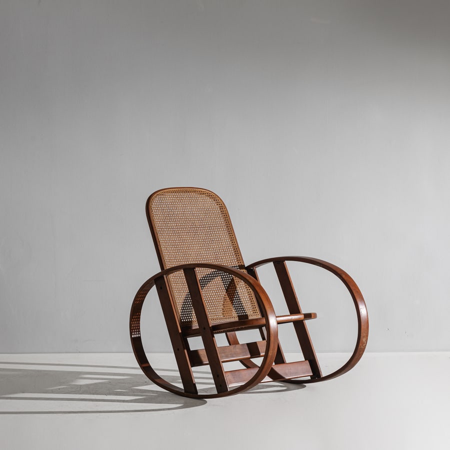 ANTONIO VOLPE: Poltrona a dondolo con poggiapiedi integrato. Legno di faggio curvato, paglia di Vienna. Produzione Antonio Volpe anni '70 ca. cm 99x67x102 A ROCKING CHAIR BY A. VOLPE Buone condizioni generali.