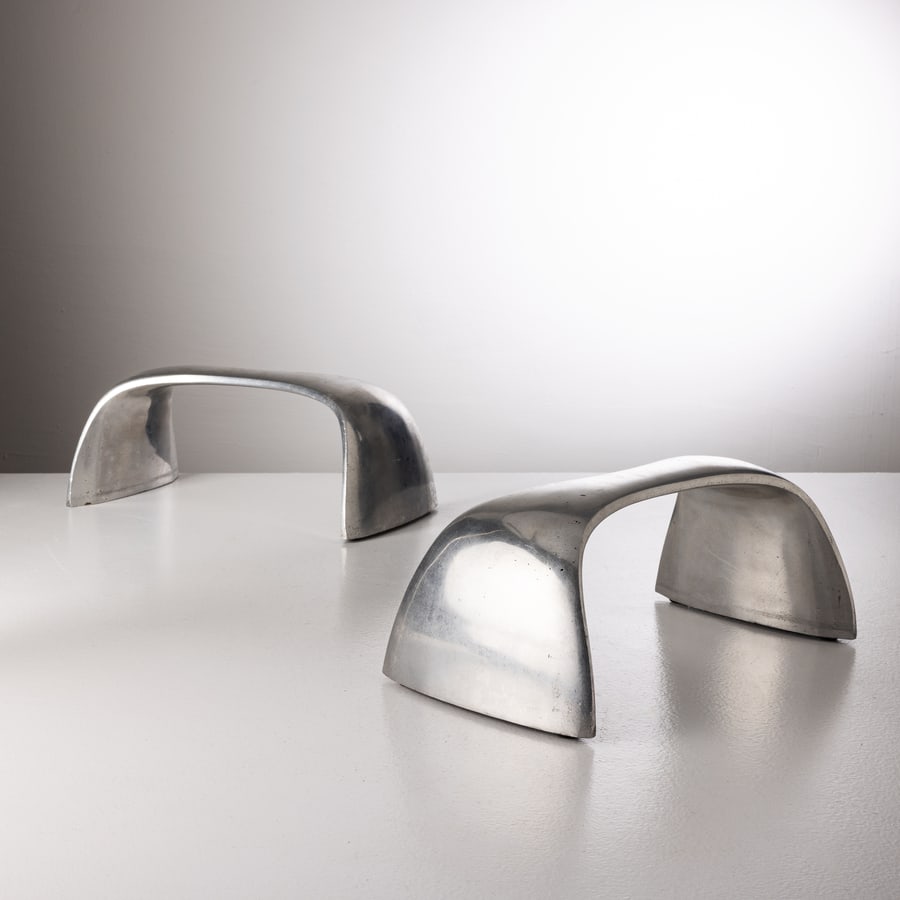 MANIFATTURA ITALIANA: Due sgabelli ; scultura. Alluminio pressofuso lucidato. Italia anni '90. cm 16,5x40,5x23 A PAIR OF ITALIAN SCULPTURAL STOOLS Condizioni molto buone. righe, graffi, segni d'usura, lieve ossidazione ed