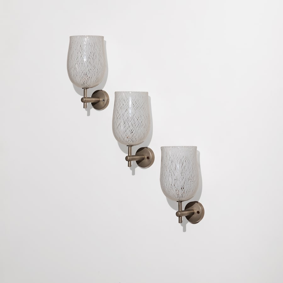 PAOLO VENINI (ATTRIB. A): Tre lampade da parete. Ottone nichelato, vetro reticello. Murano anni '40. cm 23x13x15 THREE WALL LIGHTS ATTRIBUTED TO P. VENINI Buone condizioni generali. Piccole righe, leggeri graffi, normali segni