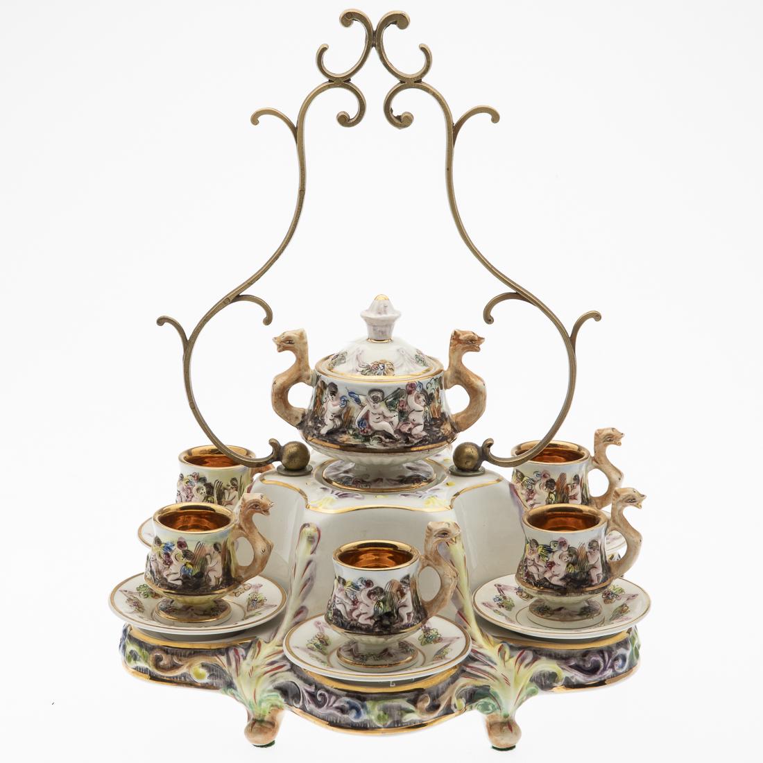 Capodimonte Chocolate Service: Property from a Private Collection, Hilton Head Island, SC comprising 6 cups and saucers, a chocolate pot, and a display tray with decorative metal handle, decorated with flowers and cherubs, all mark