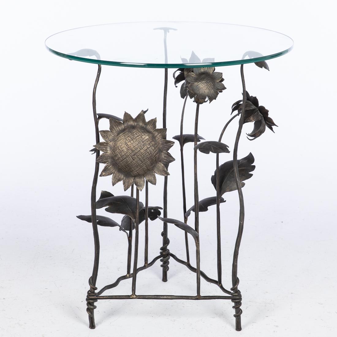 John Boyd Smith, Glass Top Wrought Iron Table: Property of a Private Collection, Savannah, GA (Savannah, 20th/21st Century), the circular glass top above a base issuing sunflowers. Size with glass: H. 35 1/2 in. x W. 29 1/2 in. John Boyd Smith is 