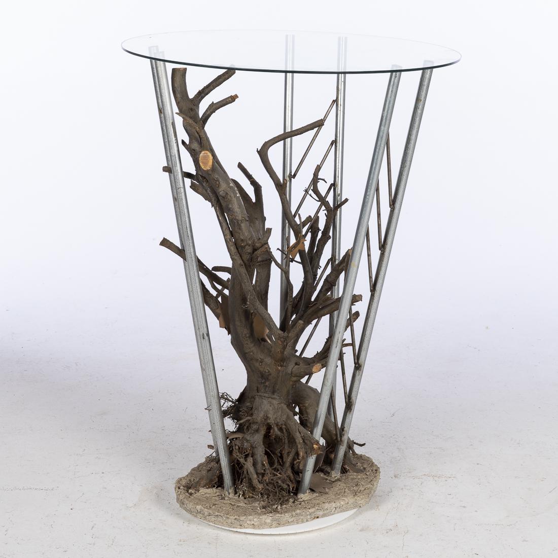John Bucci, Metal and Wood Circular Table Base: (Illinois, 1935-2019), signed, on tree branch. GLASS NOT INCLUDED. Size without top: H. 42 1/4 in. x W. 23 1/2 in. John Bucci, who worked from a studio in Chicago, created concept cars, one of which "