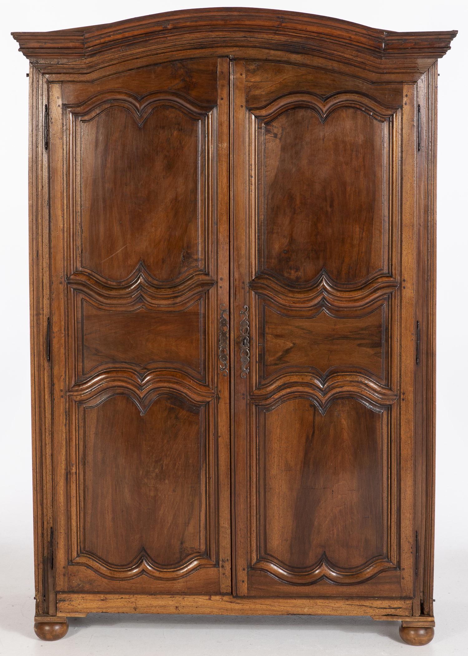 Louis XV Provincial Walnut Armoire, 18th/19th C: Louis XV Provincial Walnut Armoire, 18th/19th Century, the arched cornice above paneled doors, opening to an interior fitted with later shelves, raised on bun feet. MEASURMENTS: Height: 7 ft. 6 in. x 