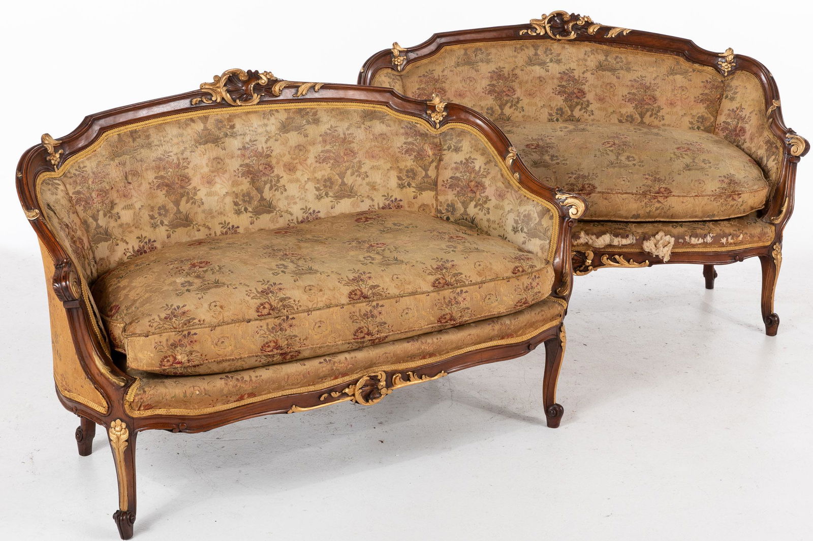 Pair of Louis XVI Style Walnut Settees, 19th Century: Property from a Savannah, GA Estate Description: Pair of Louis XVI Style Walnut Settees, 19th Century, each with C-scroll and floral carved crest continuing to sides centering a loose-fitted cushi