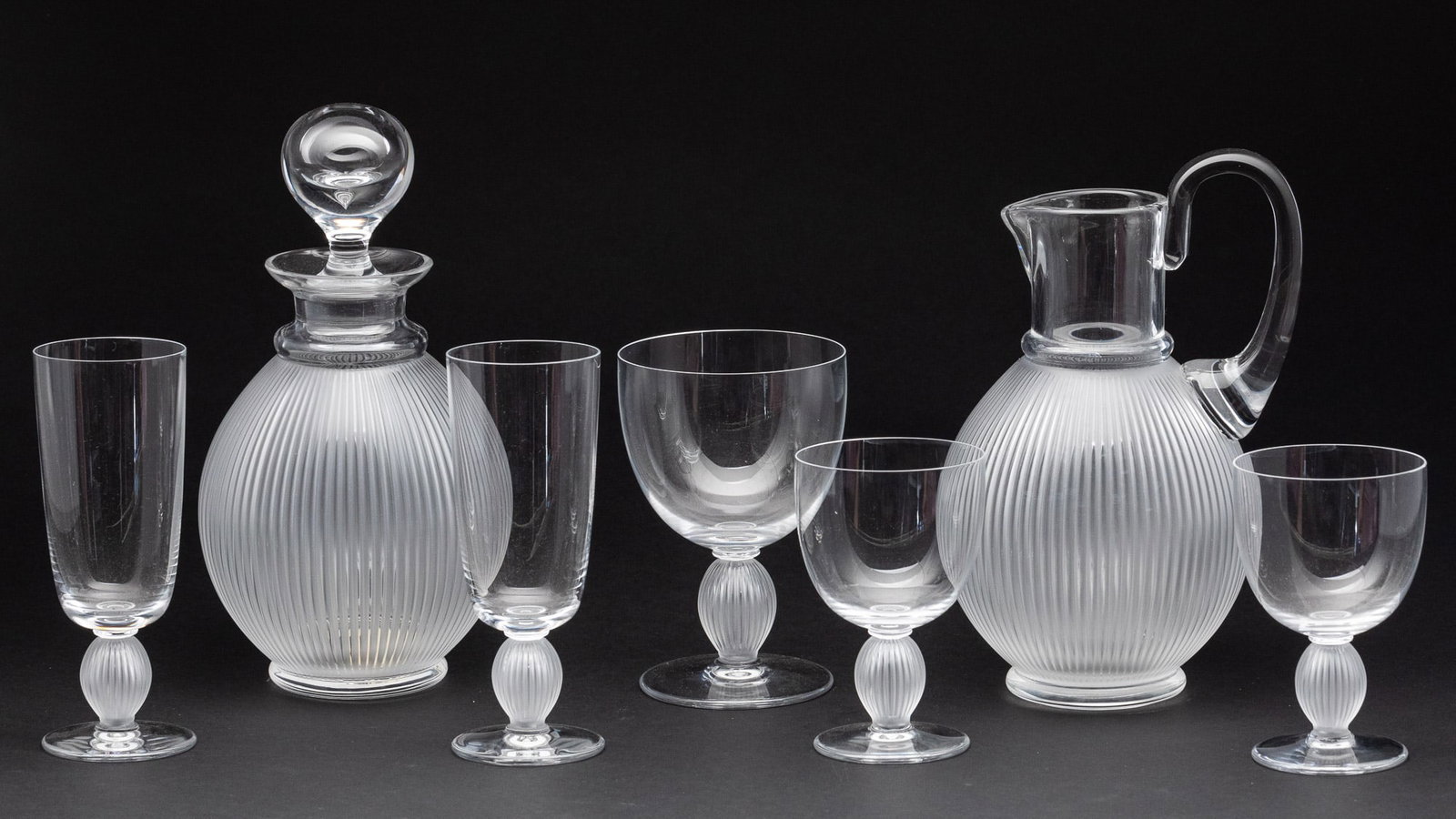 Lalique Langeais Decanter, Pitcher & 5 Glasses: Description: Lalique Langeais Pattern Decanter, Pitcher & 5 Glasses, comprising a pitcher (9 in. x 6 in. x 5 in.), decanter with stopper, two 6 3/8 in. champagne glasses, 6 5/8 in. wine glass, an