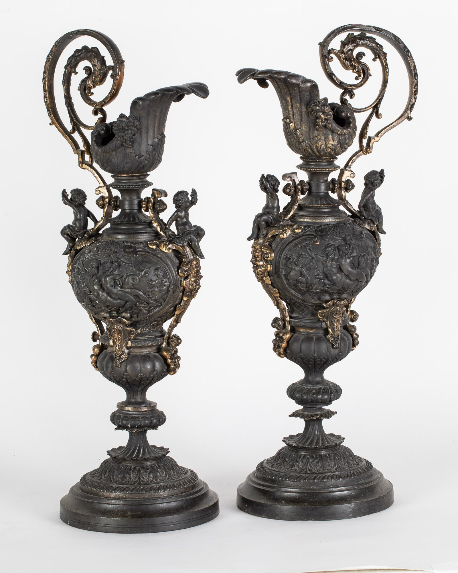 Pair of Renaissance Style Metal Ewers: Property from a Private Collection, Jacksonville, FL Description: Pair of Renaissance Style Metal Ewers, decorated with putti and gold accents, one formerly fitted as a lamp. Measurement