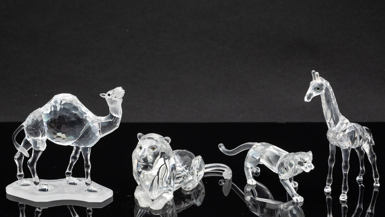 Swarovski Crsytal Giraffe, Camel, Lion and Jaguar: Property from a South Carolina Estate Description: Swarovski Crsytal Giraffe, Camel, Lion and Jaguar, comprising a 4 5/8 in. camel on a base, a 5 1/2 in. giraffe, a 2 1/2 in. lion and a 1 7/8 in.