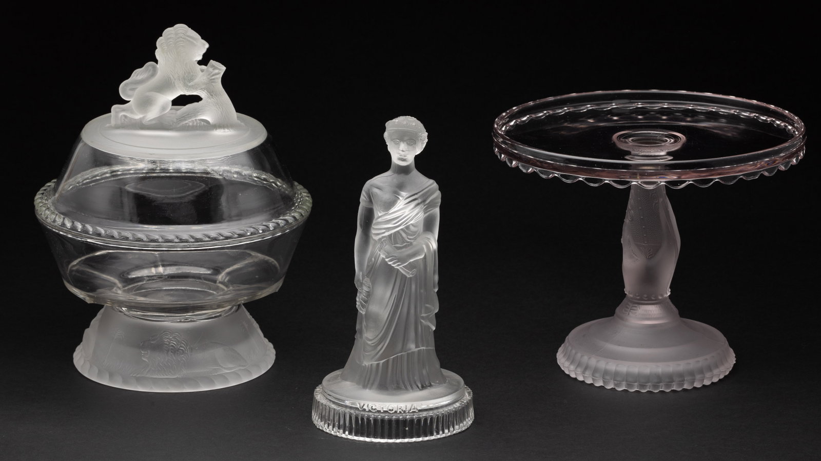 Pressed and Frosted Glass Decorative Articles: Description: Group of Pressed and Frosted Glass Decorative Articles , comprising John Derbyshire pressed glass figure of a young Victoria circa 1874, hand-form cake stand, and a lidded compote.
