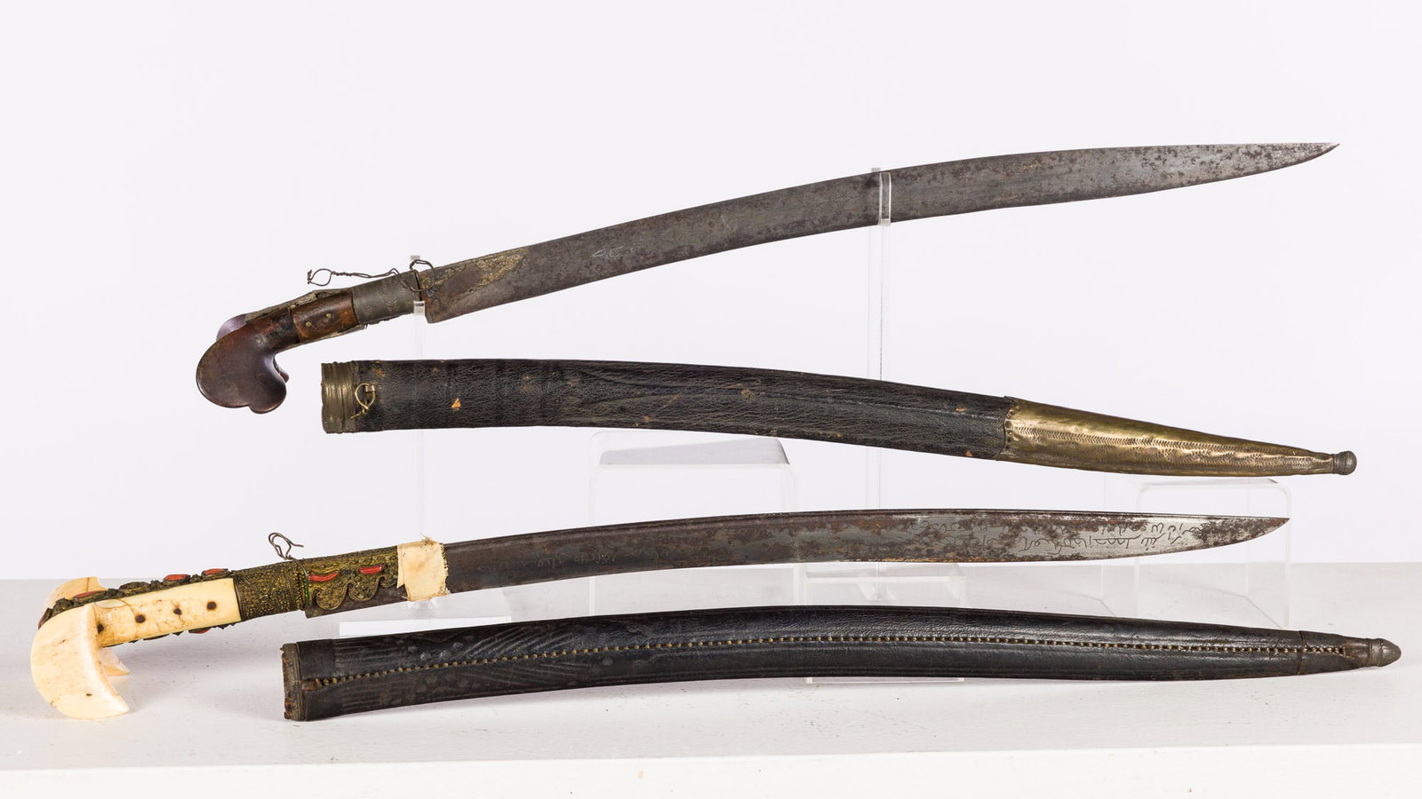 Two Middle Eastern Sabers: Property of a Diplomatic World-Traveling Family Description: Two Middle Eastern Sabers, a wood handled saber with leather sheath and metal mounts with engraved blade, and a bone, metal and shell