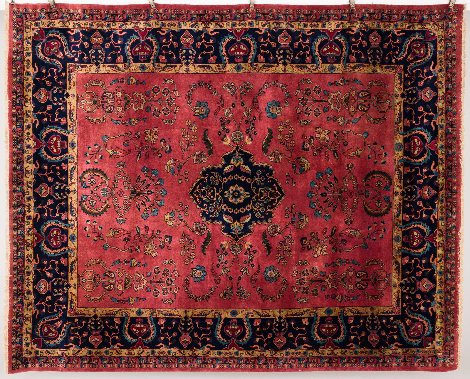 Persian Rug: Property from the Estate of Ann Lytle, Savannah, GA Description: Persian Rug in tones of raspberry red with a blue border, in tones of dark blue, light blue, cream and ochre on a raspberry ground