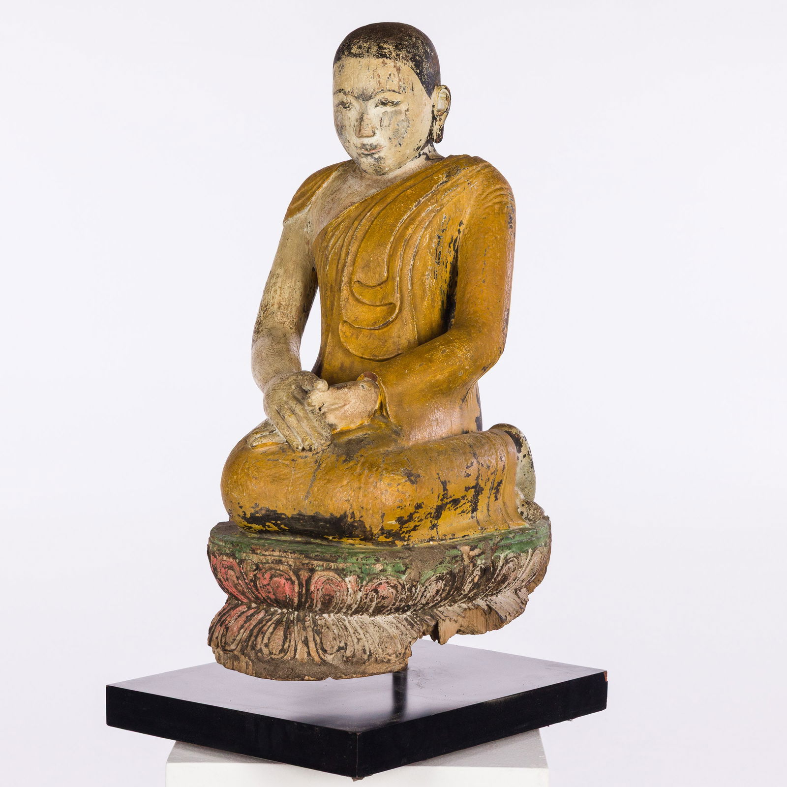 Asian Carved Wood Buddha: Description: Asian Carved Wood Buddha, carved and painted wood kneeling buddha figure on lotus flower base, mounted on a rectangular laminated wood stand. Measurements: Height: