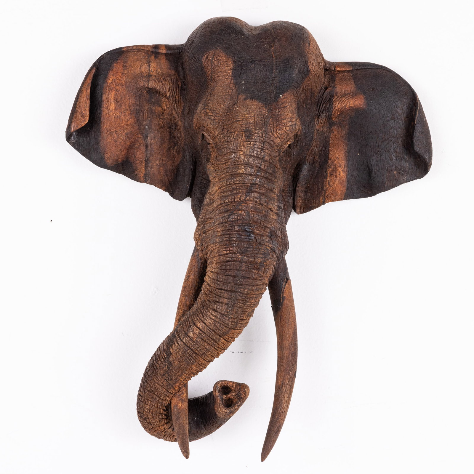 Carved Wood Elephant Head: Property of John E. Floyd, Savannah, GA Description: Carved Wood Elephant Head, illegibly inscribed/signed on verso, with wire hanger. Measurements: Height: 17 1/2 in. x Width: