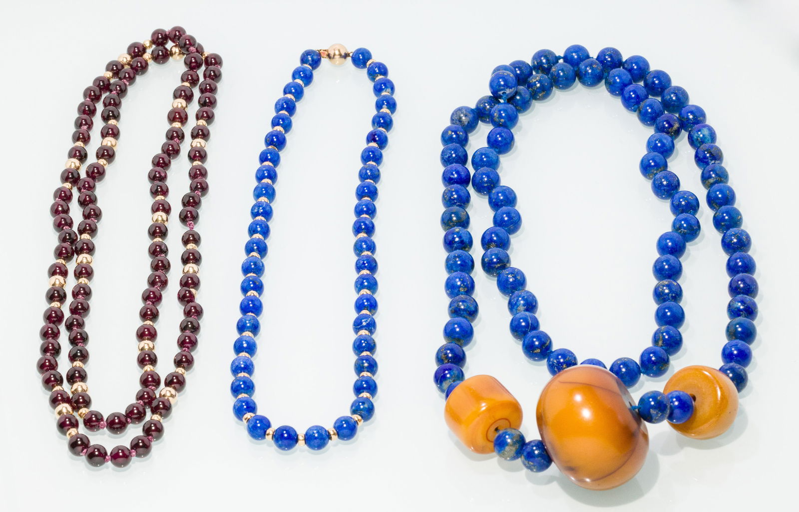 Two Beaded Lapis Necklaces & Beaded Garnet Necklace: Description: Two Beaded Lapis Necklaces and a Beaded Garnet Necklace, comprising a lapis and Bakelite beaded necklace (35 in.), a lapis and 14K gold beaded necklace, marked '14K' on clasp (17 1/2