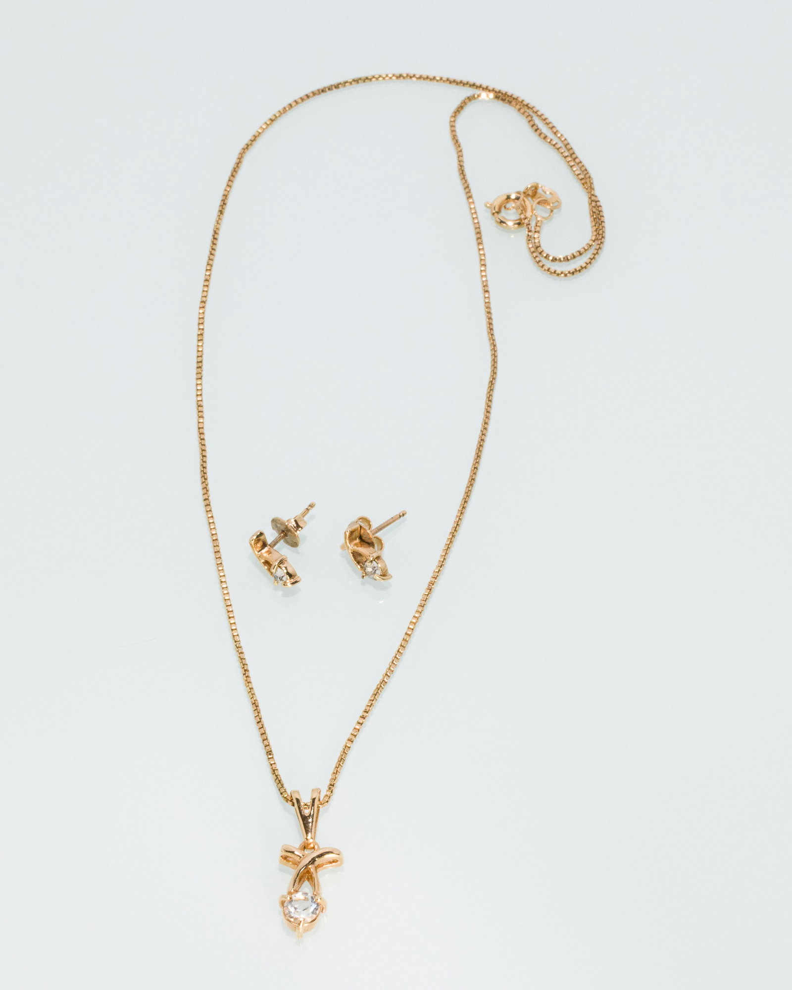 10K and Cubic Zirconia Necklace and Earrings: Description: 10K and Cubic Zirconia Necklace and Earrings, gold necklace featuring a cubic zirconia stone on a gold chain, together with a pair of matching stud earrings, the earrings and pendant