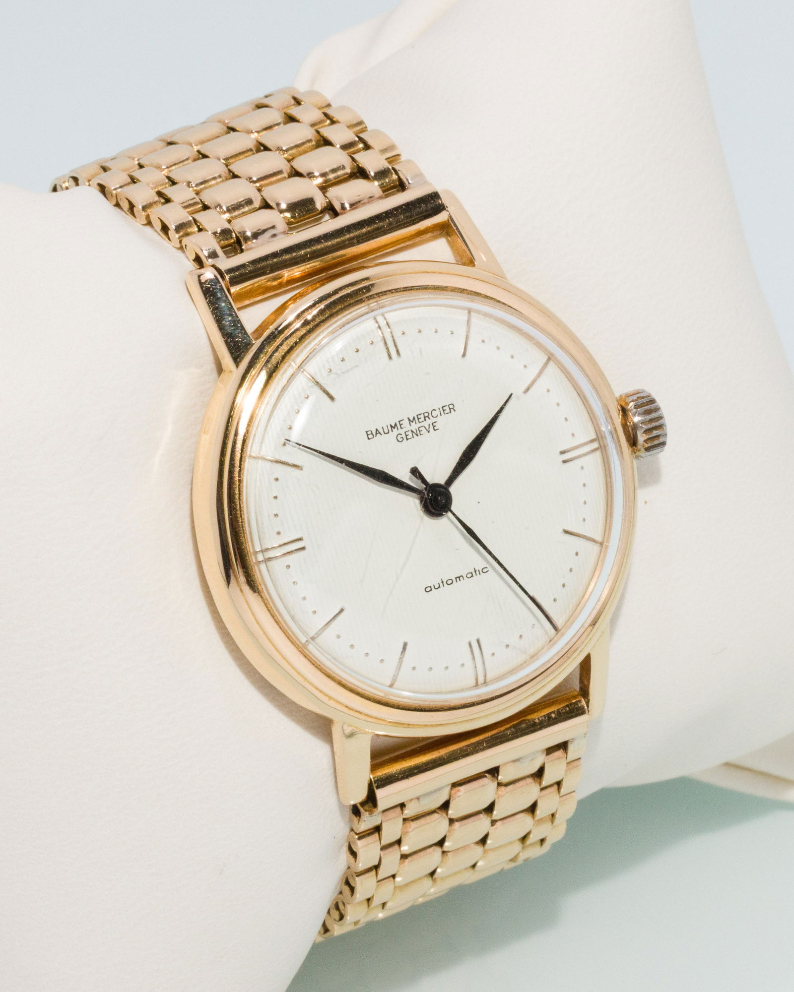 Baume Mercier 18K Gold Men's Watch: Description: Baume Mercier 18K Gold Men's Watch, 18K yellow gold case with white dial with stick hour markers on a flat link gold bracelet, the back of case marked 'Antimagnetic, incabloc, water