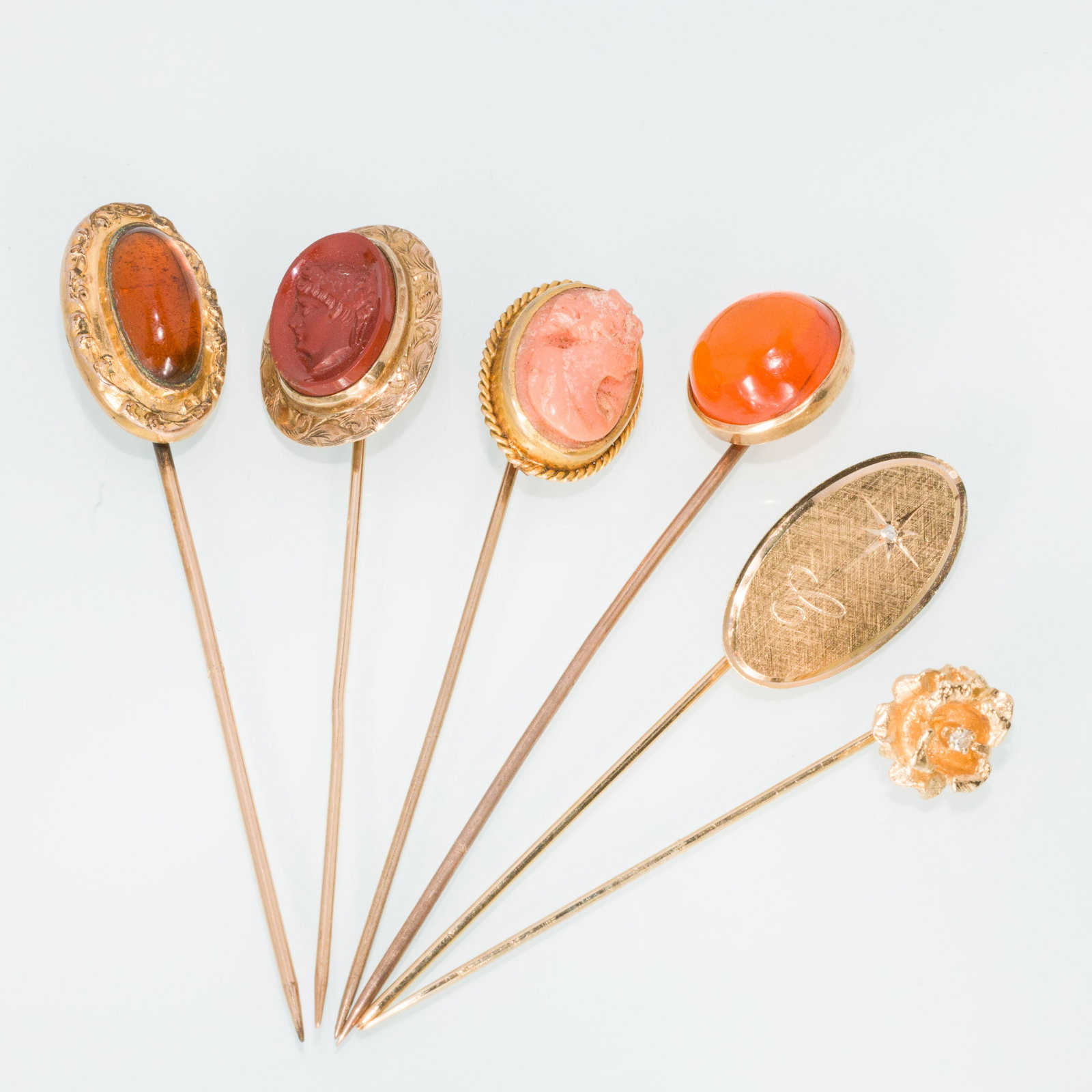 Group of 6 Gold Stick Pins: Property from a Private Collection, Jacksonville, FL Description: Group of 6 Gold Stick Pins, comprising a 18K pin with cameo (marked '18K', 2.33 grams), a pin with orange glass cabochon (unmarked