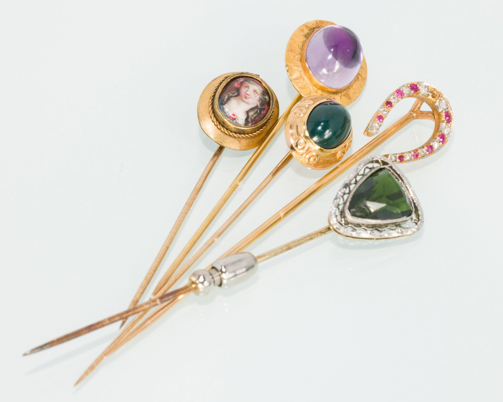 Group of 5 Gold Stick Pins: Property from a Private Collection, Jacksonville, FL Description: Group of 5 Gold Stick Pins, comprising a 10K pin with oval amethyst cabochon (marked '10K', 2.39 grams), a 14K pin with jade caboc