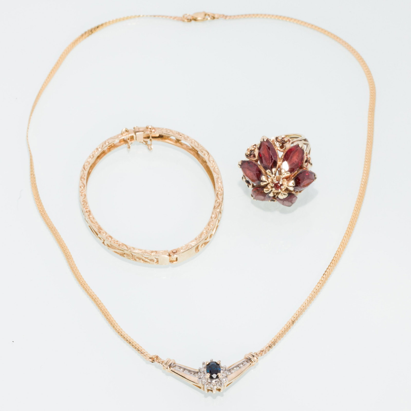 Sapphire Diamond Necklace, Childs Bangle, Garnet Ring: Description: 10K Sapphire & Diamond Necklace, 14K Garnet Ring & 10K Childs Bangle, including a 10K yellow gold necklace with central oval sapphire with diamond halo and channel set diamonds on a
