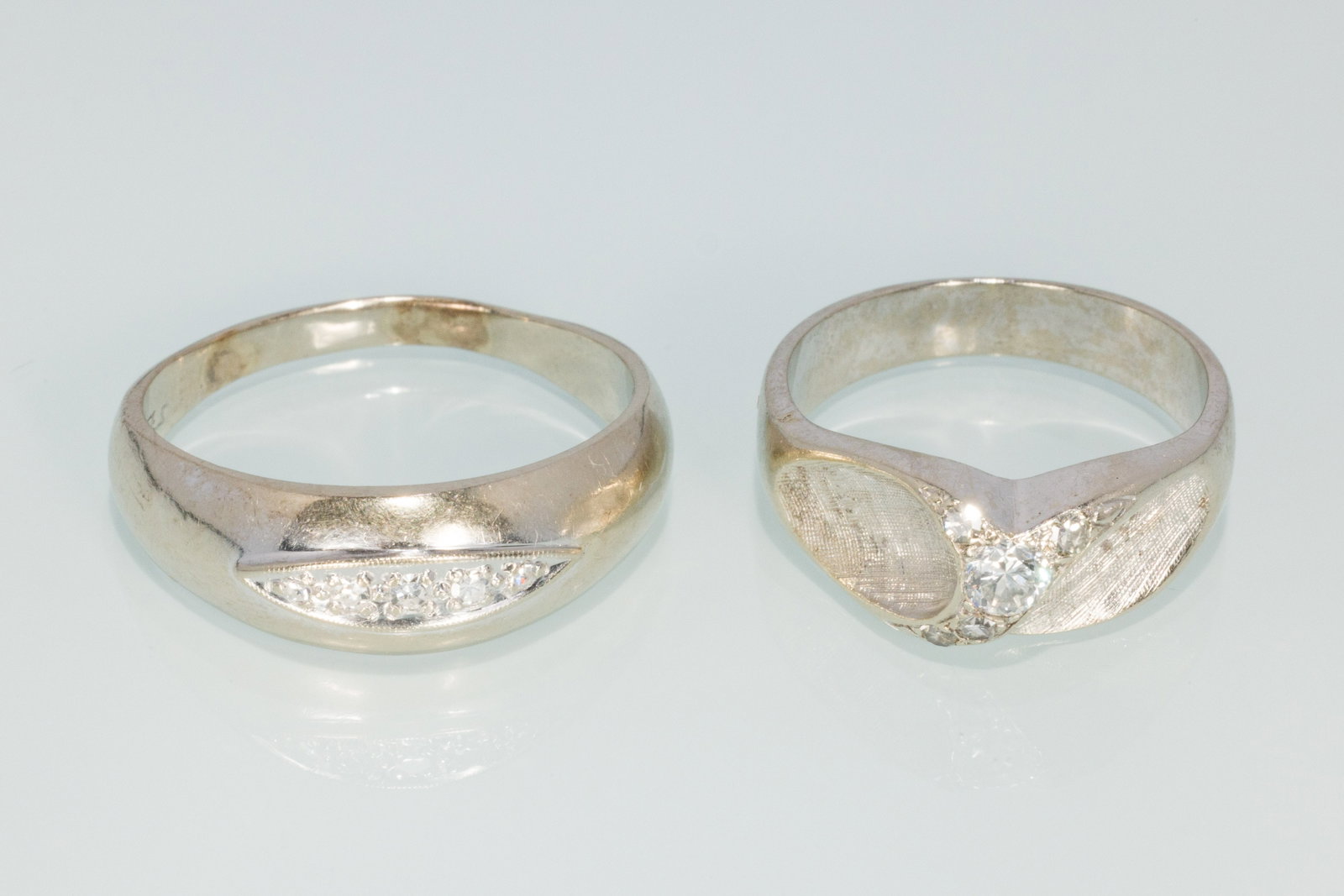 Two 14K and Diamond Contemporary Men's Rings: Property from a Private Collection, Jacksonville, FL Description: Two 14K and Diamond Contemporary Men's Rings, comprising a 14K white gold band featuring bead set round diamonds, size 9.75 (marke