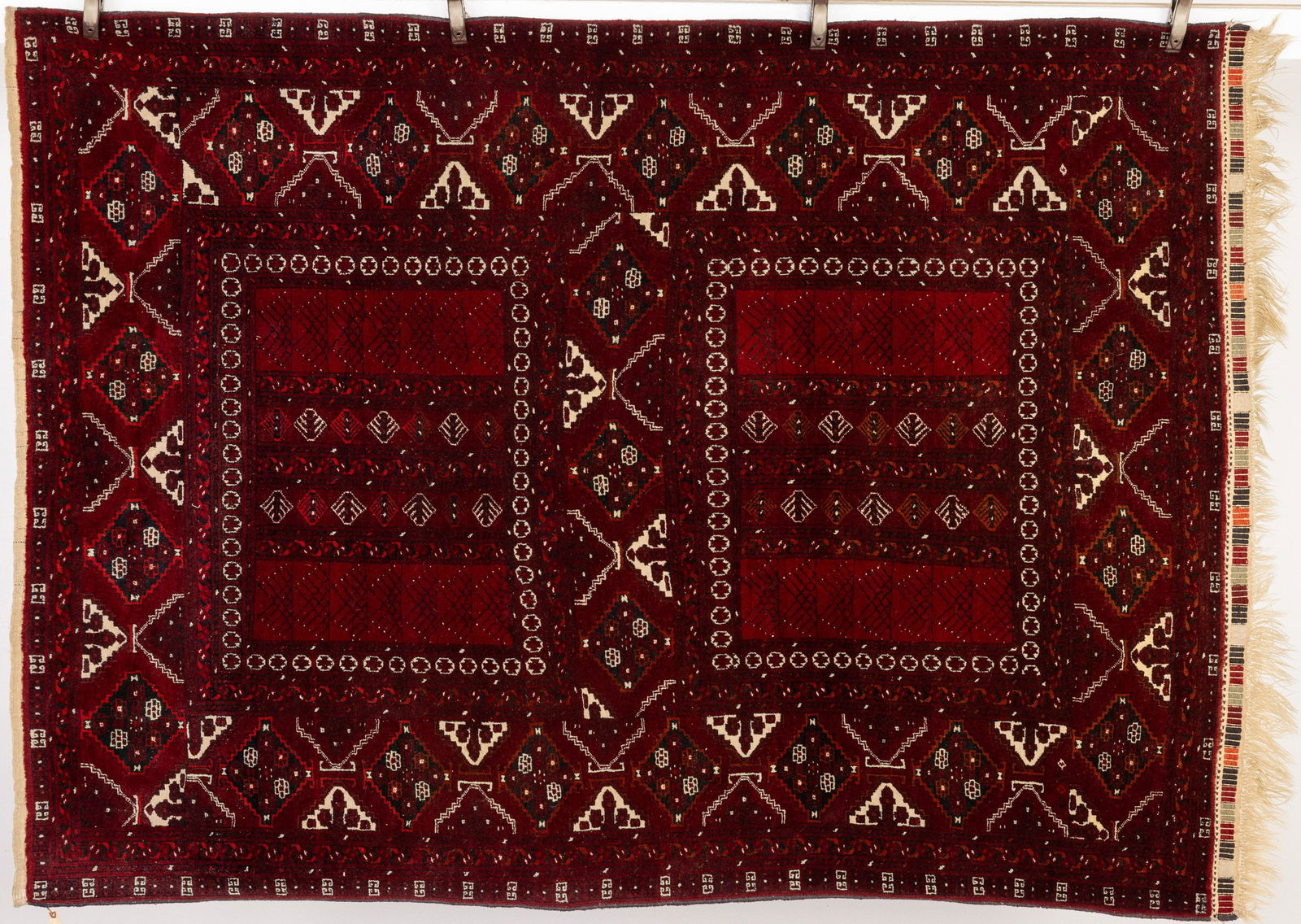 Tribal rug: Property from the Estate of Arthur B. Kouwenhoven Jr., Savannah, GA Description: Tribal rug, in tones of cream, black, and red on maroon ground with fringe on one edge. Measurements: