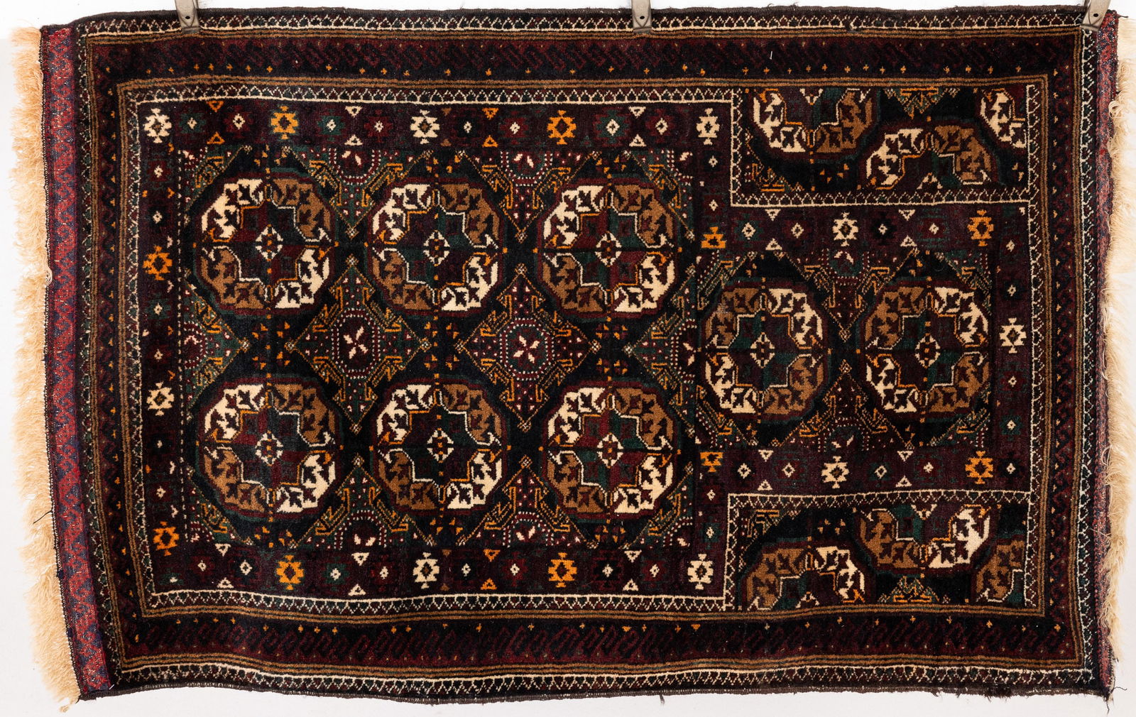 Small Belouch Persian Prayer Rug: Property from the Estate of Arthur B. Kouwenhoven Jr., Savannah, GA Description: Small Belouch Persian Prayer Rug, in tones of dark green, black, orange, and ochre on a dark green ground.
