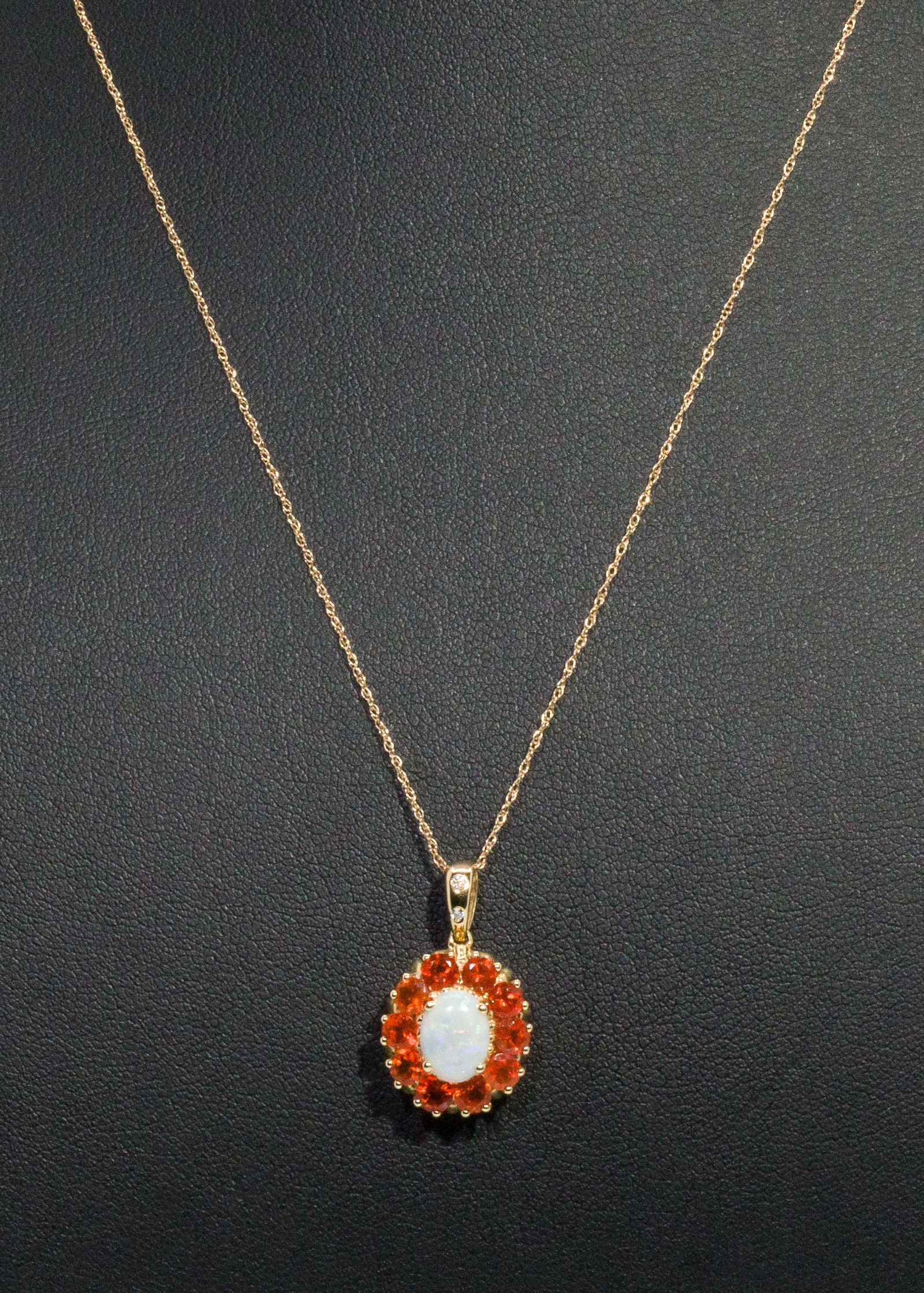 14K Australian Opal Pendant: Description: 14K Australian Opal Pendant, 14K yellow gold pendant featuring central oval cabochon (approx. 8 mm x 6 mm) surrounded by 10 round orange gems (approx. 0.87 cts) with two small diamon