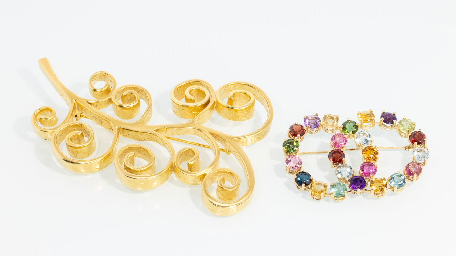 14K and Gemstone Pin and a Givenchy Gilt-Metal Pin: Property from a Private Collection, Jacksonville, FLDescription: 14K and Gemstone Pin and a Givenchy Gilt-Metal Pin, 14K yellow gold double ring brooch featuring an array of colored gemstones,