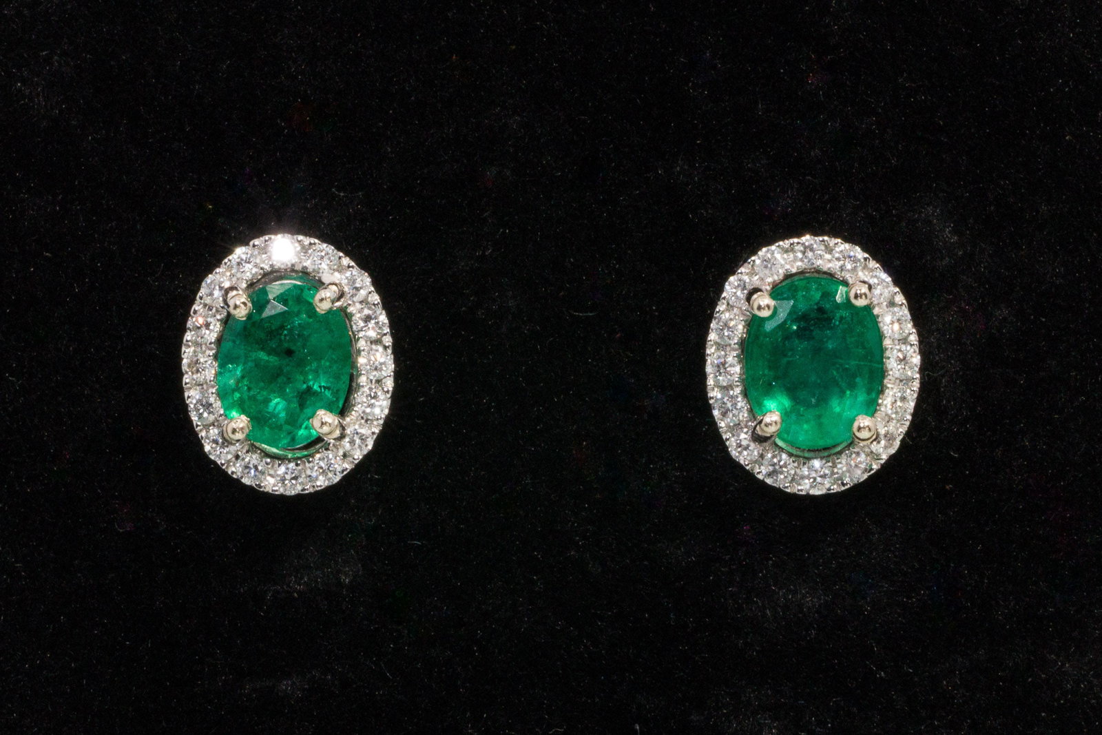 Emerald and Diamond 14K Stud Earrings: Description: Emerald and Diamond 14K Stud Earrings, 14K white gold stud earrings featuring oval cut emeralds (approx. 2.5 cts total, approx. 6.56 mm x 5.23 mm and 6.8 mm x 5.43 mm) with diamond halo